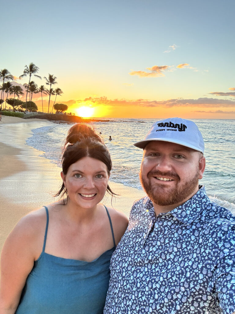Couple at sunset on Kauai beach with palm trees